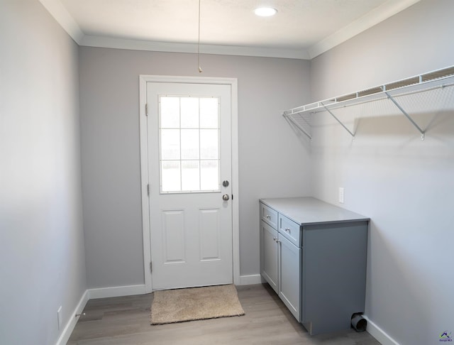 washroom with light wood-type flooring, ornamental molding, and cabinets