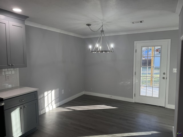 unfurnished dining area featuring dark hardwood / wood-style floors, an inviting chandelier, and ornamental molding