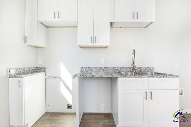 kitchen with light stone counters, sink, and white cabinets