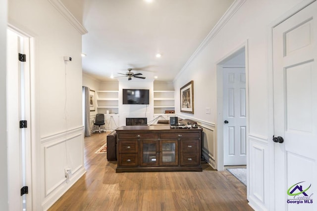 interior space with dark brown cabinetry, ceiling fan, built in features, hardwood / wood-style floors, and ornamental molding