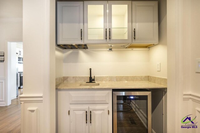 bar featuring ornamental molding, sink, white cabinets, light hardwood / wood-style floors, and wine cooler