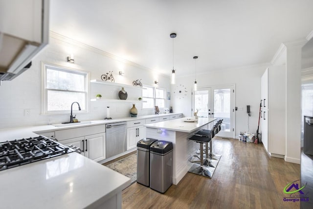 kitchen with pendant lighting, sink, stainless steel dishwasher, a kitchen island, and white cabinetry