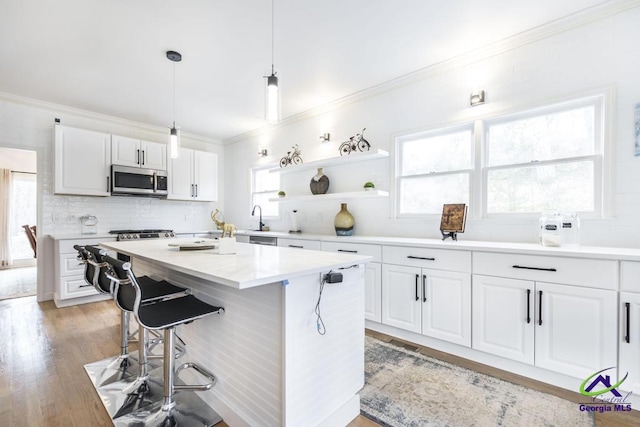 kitchen featuring decorative backsplash, pendant lighting, white cabinets, light hardwood / wood-style floors, and an island with sink