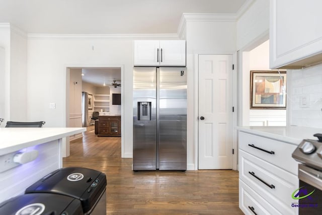 kitchen with dark wood-type flooring, range, white cabinets, ornamental molding, and stainless steel fridge with ice dispenser