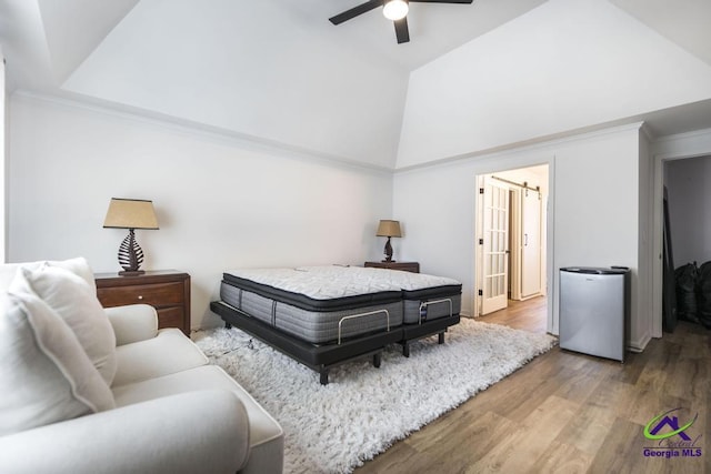 bedroom with hardwood / wood-style floors, refrigerator, a raised ceiling, vaulted ceiling, and ceiling fan