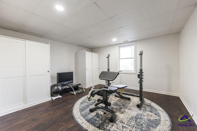 exercise area with a paneled ceiling and dark hardwood / wood-style floors