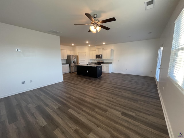 unfurnished living room featuring ceiling fan, sink, and dark wood-type flooring