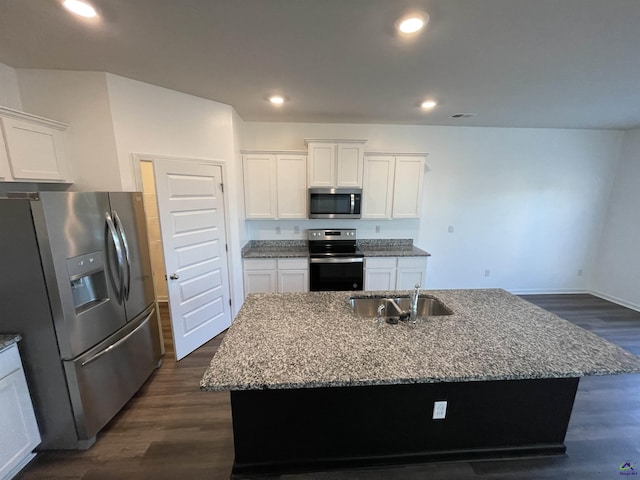 kitchen featuring light stone counters, white cabinetry, an island with sink, and appliances with stainless steel finishes