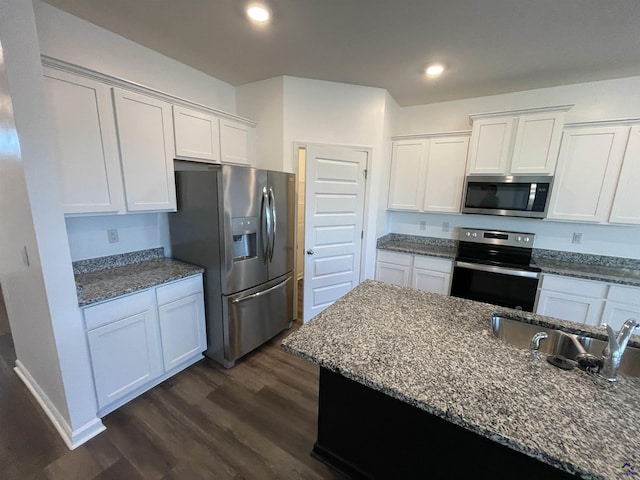 kitchen with white cabinetry, sink, stainless steel appliances, dark hardwood / wood-style floors, and dark stone counters