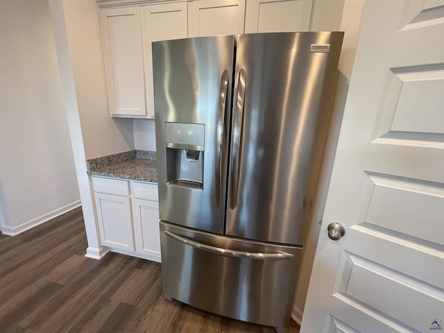 kitchen featuring white cabinets, stainless steel fridge with ice dispenser, dark wood-type flooring, and dark stone counters