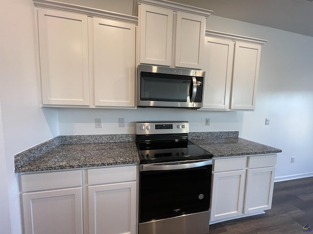 kitchen with white cabinets, dark hardwood / wood-style floors, dark stone countertops, and appliances with stainless steel finishes