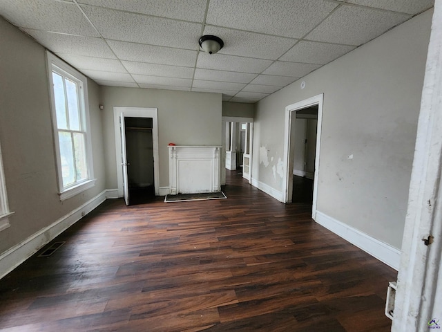 unfurnished living room featuring a drop ceiling and dark wood-type flooring