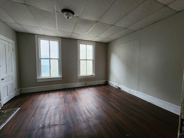 unfurnished room featuring dark hardwood / wood-style floors and a drop ceiling