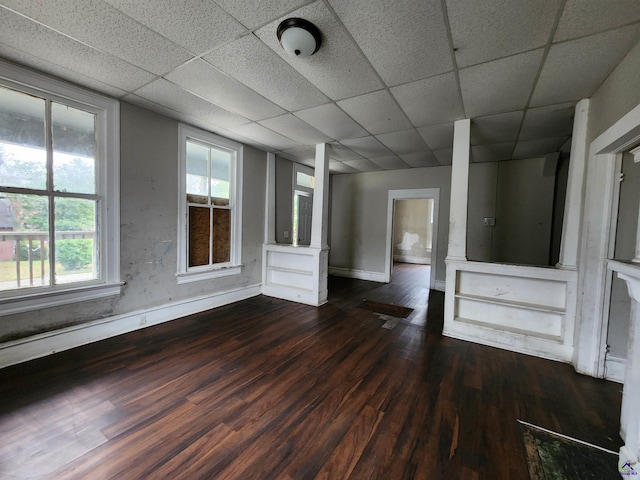 unfurnished living room featuring a paneled ceiling and dark wood-type flooring