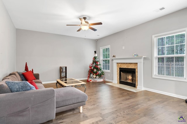 living room featuring a tile fireplace, hardwood / wood-style flooring, and ceiling fan