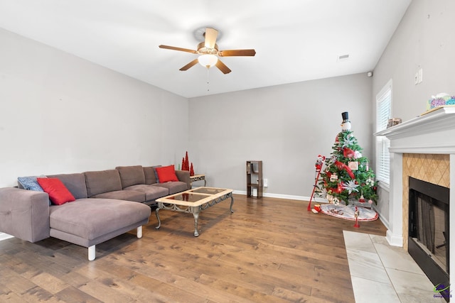 living room featuring a tile fireplace, hardwood / wood-style floors, and ceiling fan