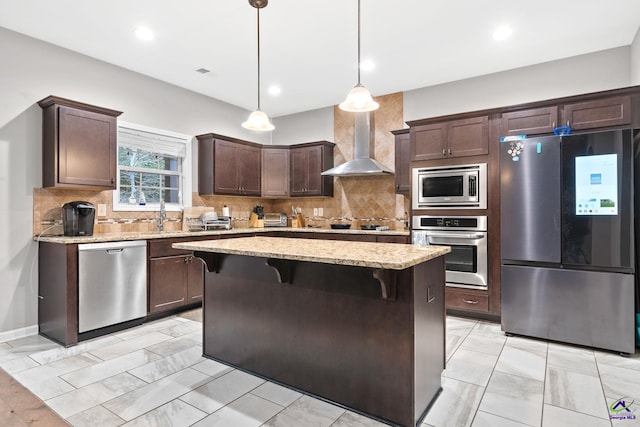 kitchen with pendant lighting, a center island, wall chimney exhaust hood, dark brown cabinetry, and stainless steel appliances