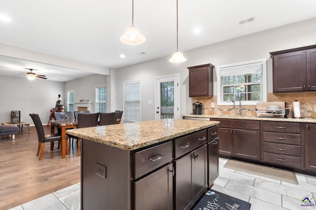 kitchen with tasteful backsplash, sink, a kitchen island, and decorative light fixtures