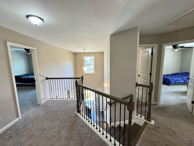 corridor with attic access, baseboards, carpet flooring, and an upstairs landing