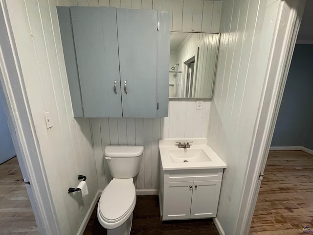 bathroom with wooden walls, hardwood / wood-style floors, vanity, and toilet