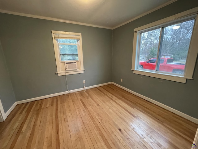 spare room with a wealth of natural light, ornamental molding, and light wood-type flooring