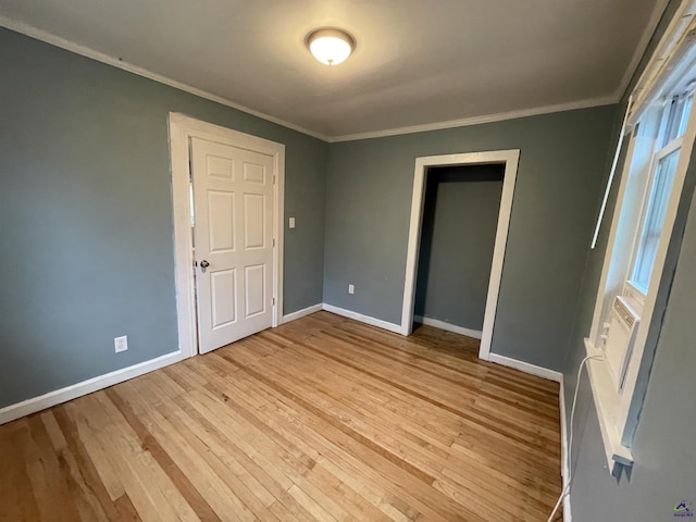 unfurnished bedroom featuring light hardwood / wood-style floors, crown molding, and a closet