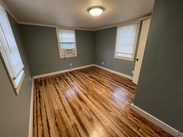 spare room featuring cooling unit, wood-type flooring, and crown molding