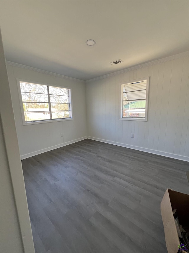 empty room featuring ornamental molding and dark wood-type flooring