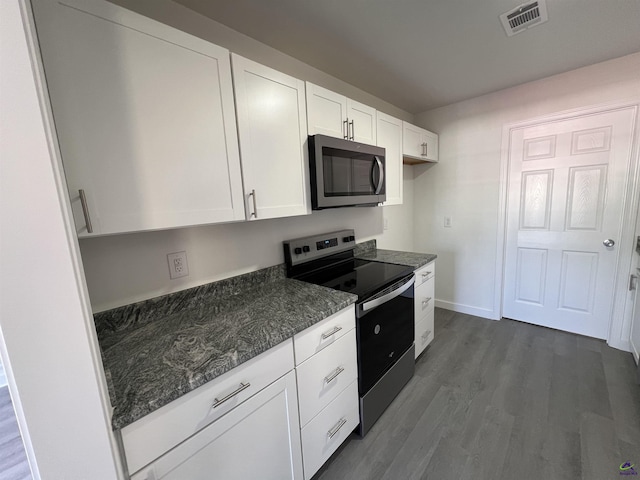 kitchen with dark stone countertops, white cabinetry, dark hardwood / wood-style flooring, and appliances with stainless steel finishes