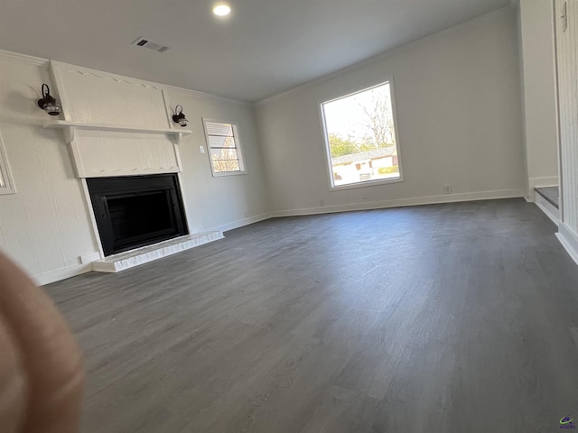 unfurnished living room featuring dark hardwood / wood-style flooring, ornamental molding, and a wealth of natural light