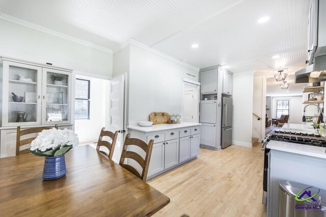 kitchen with gray cabinetry, ornamental molding, light hardwood / wood-style floors, and appliances with stainless steel finishes