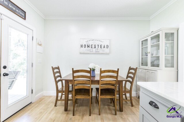 dining room with crown molding and light hardwood / wood-style flooring