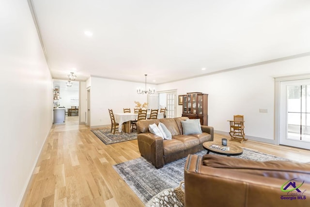 living room with a chandelier, light wood-type flooring, and crown molding