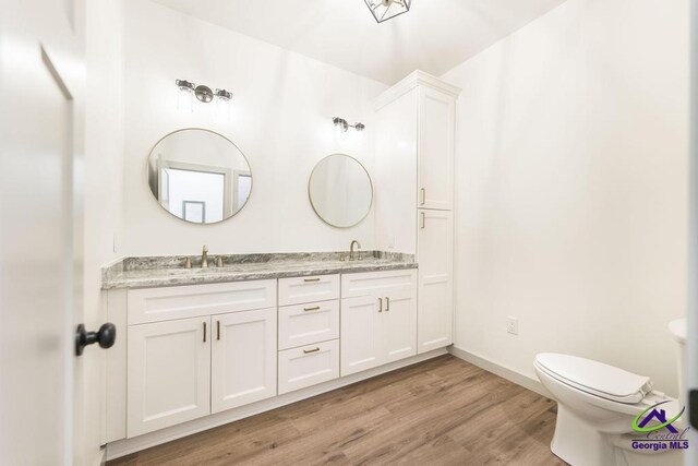 bathroom with hardwood / wood-style floors, vanity, and toilet