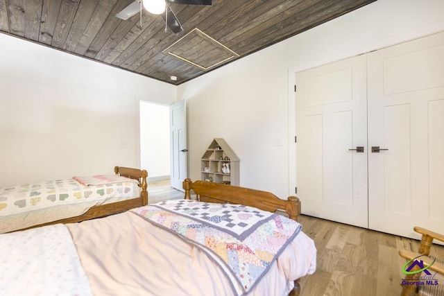 bedroom with ceiling fan, light hardwood / wood-style floors, wood ceiling, and a closet