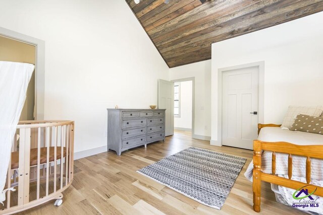 bedroom featuring high vaulted ceiling, wooden ceiling, a crib, and light wood-type flooring