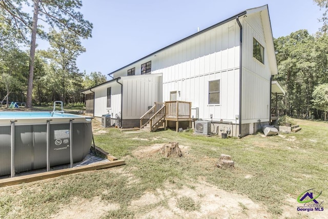 rear view of house with a lawn, ac unit, and central AC unit