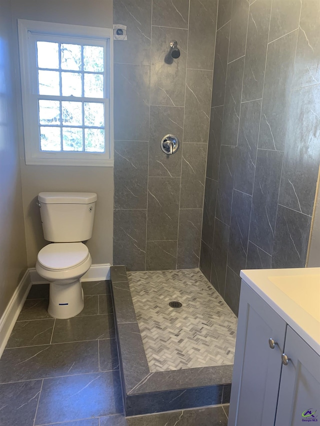 bathroom featuring vanity, tiled shower, and toilet