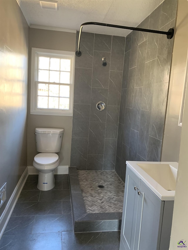 bathroom featuring vanity, a textured ceiling, toilet, and tiled shower