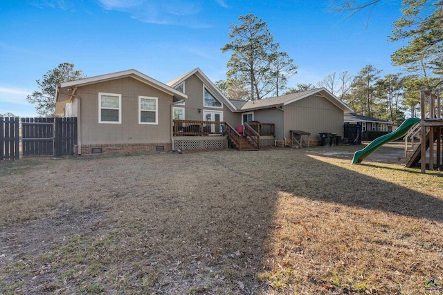 back of property featuring a wooden deck, a playground, and a lawn