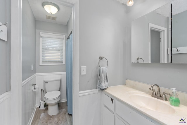 bathroom featuring toilet, vanity, a textured ceiling, and hardwood / wood-style floors