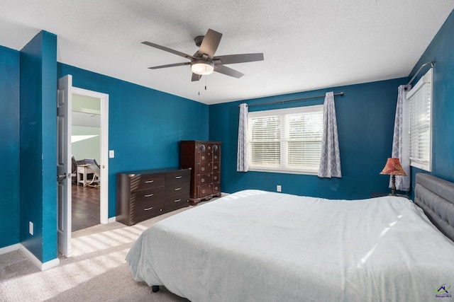 bedroom with a textured ceiling, ceiling fan, and light carpet