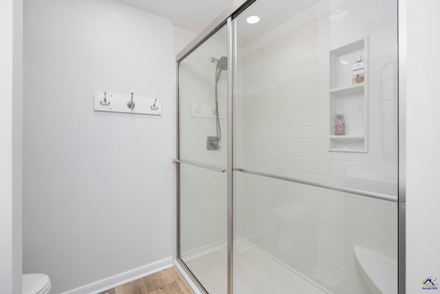 bathroom featuring toilet, an enclosed shower, and wood-type flooring