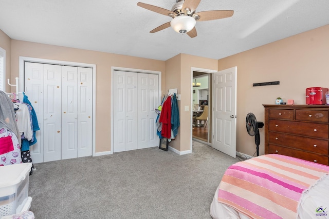 bedroom featuring two closets, ceiling fan, and light carpet