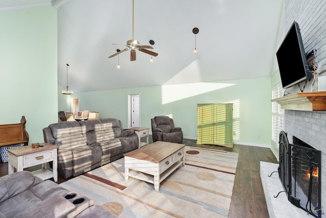 living room with vaulted ceiling, wood-type flooring, crown molding, ceiling fan, and a brick fireplace