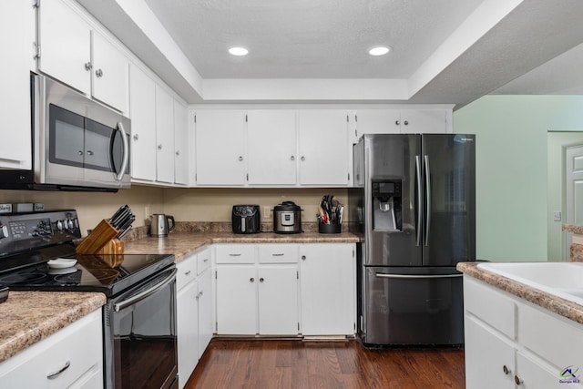 kitchen featuring sink, white cabinetry, a raised ceiling, dark hardwood / wood-style floors, and appliances with stainless steel finishes