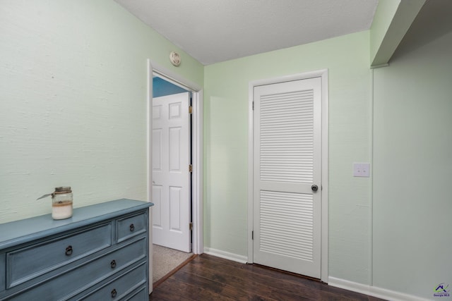 corridor with a textured ceiling and dark hardwood / wood-style flooring