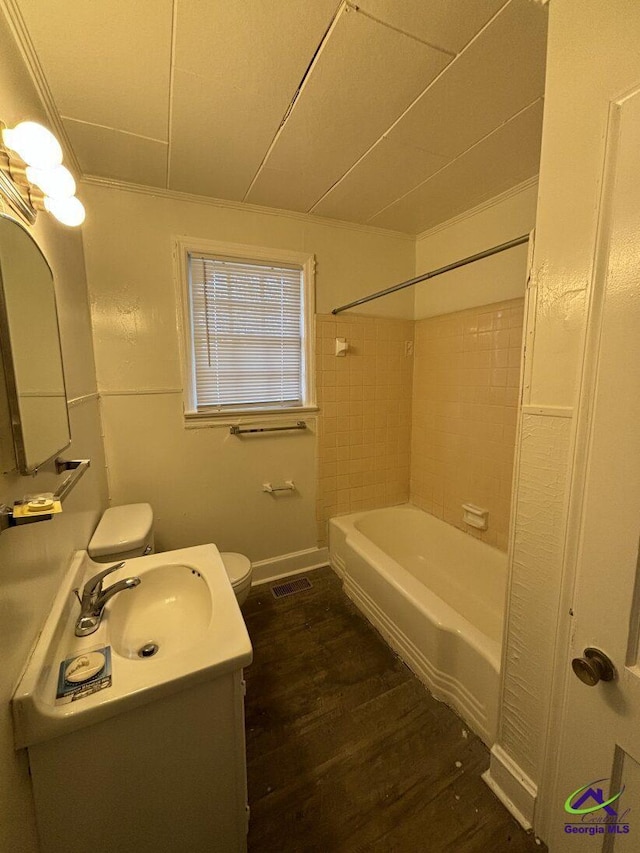 full bathroom with tiled shower / bath, hardwood / wood-style floors, toilet, vanity, and crown molding