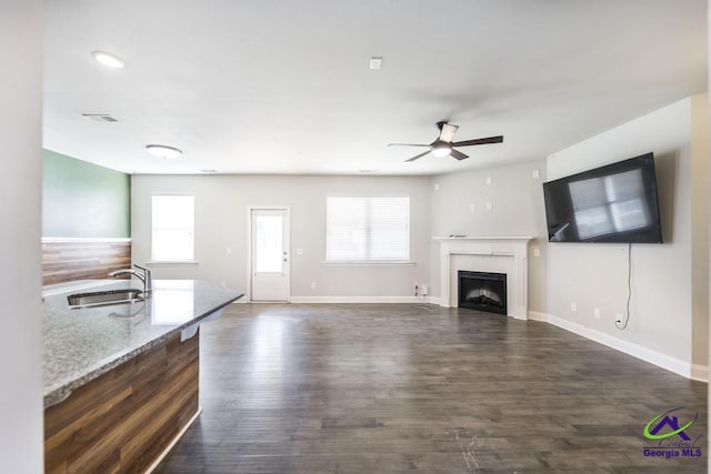 unfurnished living room featuring ceiling fan, dark hardwood / wood-style floors, a wealth of natural light, and sink