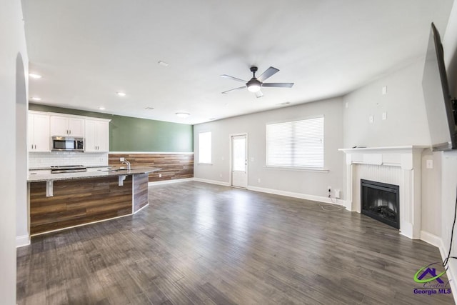 living room featuring dark wood-type flooring, ceiling fan, and sink